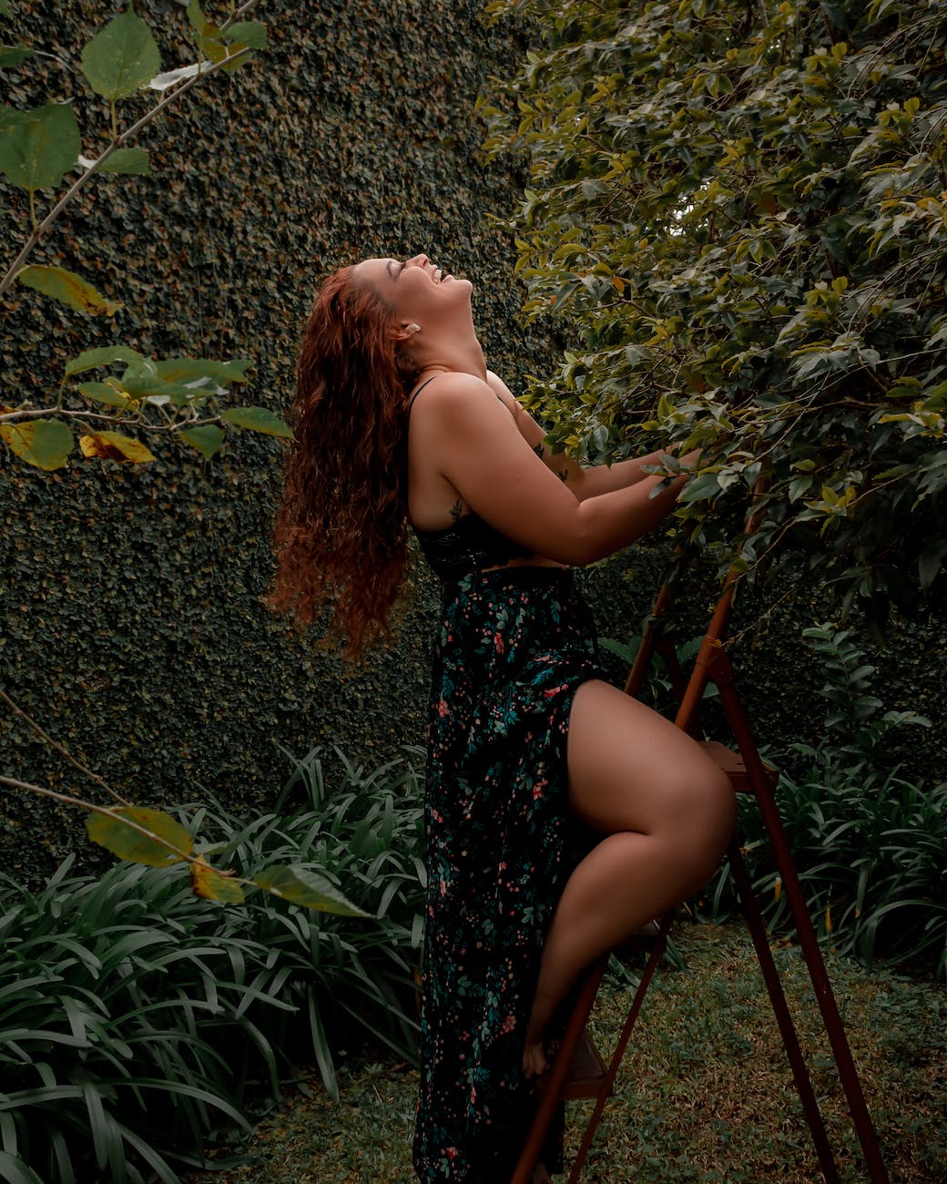 a woman in a floral dress is leaning on a ladder